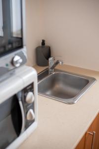 a kitchen counter with a sink and a microwave at Casa do Cédro in Vila Franca do Campo +41 photos