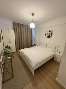 a bedroom with a white bed and a table at ABE Apartment in Craiova
