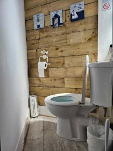 a bathroom with a toilet and a wooden wall at Driftwood Apartments Broadstairs in Broadstairs