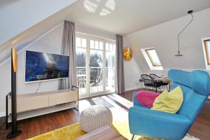 a living room with a blue chair and a television at Villa Seepferdchen Wohnung 09 in Kühlungsborn