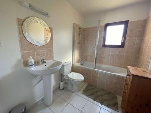 a bathroom with a sink and a toilet and a mirror at Lilas - Spacieuse maison 10 pers Jardin BBQ in Doumen