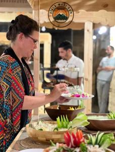 een vrouw die een bord met eten vasthoudt op een buffet bij Diala luxury wadi rum in Wadi Rum