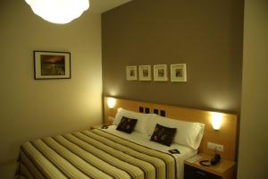 a bedroom with a bed and a lamp and pictures on the wall at Hostal Don Julio in Sanlúcar la Mayor