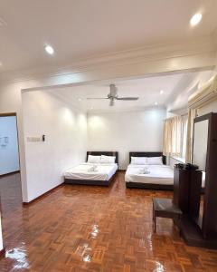two beds in a large room with wooden floors at Double Storey 4 room - Walk to Jonker Street #9pax in Melaka