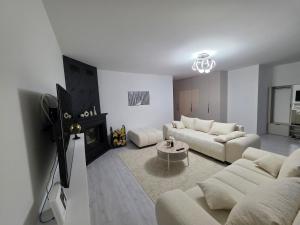 a living room with two white couches and a tv at Apartament PREMIUM z ruską banią, kominkiem i oranżerią w centrum in Brodnica