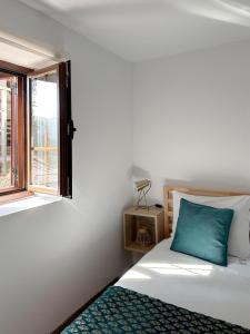 a bedroom with a bed with a blue pillow and a window at Casa do Capucho - Soajo, Gerês in Soajo