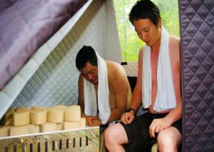 a man with a towel on his head sitting next to a mirror at アウトドア貸切別荘北軽井沢1 in Saikubo