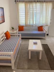 a living room with two beds and a table at Executive La Casa Di Nico 2 Bedroom Hse 2 in Mombasa