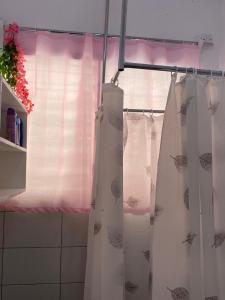 a white shower curtain in a bathroom with a window at Executive La Casa Di Nico 2 Bedroom Hse 2 in Mombasa