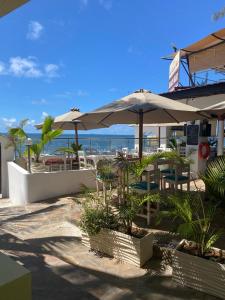 a patio with tables and umbrellas on the beach at Executive La Casa Di Nico 2 Bedroom Hse 2 in Mombasa +21 photos