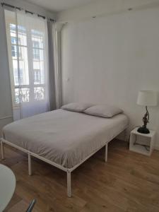 un lit dans une chambre blanche avec une fenêtre dans l'établissement Chambre privée - Vue Tour Eiffel, à Paris 6 autres photos