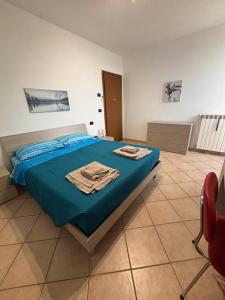 Schlafzimmer mit einem Bett mit blauer Bettwäsche und einem Stuhl in der Unterkunft B&B Canossa in Rodigo