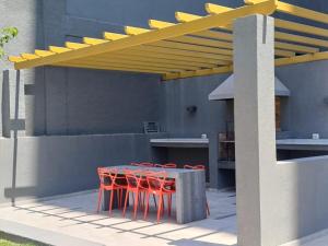 a patio with a table and red chairs under a yellow canopy at Comodidad y tranquilidad en Ñuñoa in Santiago