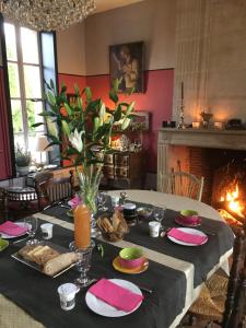 Bois-Normand-près-Lyre红房子旅馆的用餐室配有带食品的桌子和壁炉