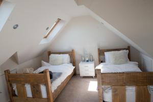 a attic bedroom with two beds and two chairs at Mumbles Seaside sleeps up 11 Pets allowed in Swansea