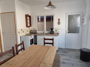 a kitchen with a wooden table and a table and chairs at Gîte Les Marettes in Beaudéduit