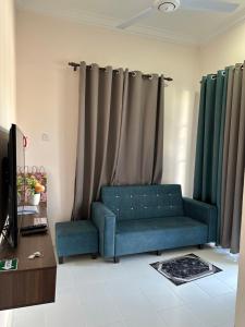 sala de estar con sofá azul y cortinas en Royale Payang Homestay, en Pulau Che' Hamid