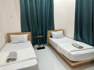 2 camas en una habitación con cortinas verdes en Royale Payang Homestay, en Pulau Che' Hamid 16 fotos más