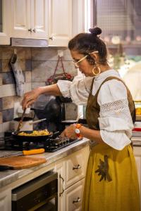 a woman in a kitchen preparing food in a pan at Happy Home in Călimăneşti