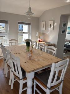 a dining room with a wooden table and white chairs at Coastal Escape - Portballintrae in Portballintrae +14 photos