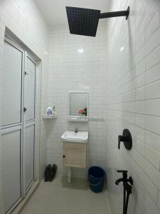 Un baño blanco con lavabo y espejo. en Homestay Al Ayyubi Medan Jaya, en Marang