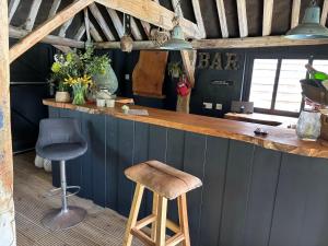 a bar with a wooden counter and two stools at Street Farmhouse in Godshill