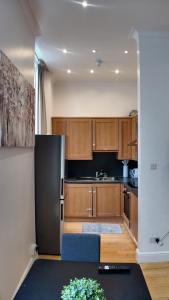 a kitchen with wooden cabinets and a black refrigerator at Cozy Apartment Sleep 5 in Berkely BK3 in London