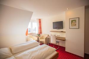 a hotel room with a bed and a desk with a television at Gästehaus Gühring in Rosenfeld