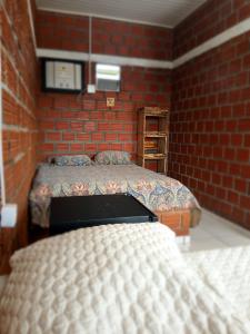 a bedroom with two beds and a brick wall at Chalé cantinho do ceu in Santo Amaro +8 photos