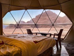 a bed in a tent with a view of the desert at Shebara Camp Wadi Rum in Wadi Rum