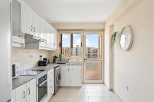 a kitchen with white cabinets and a large window at Royal Seacrest amazing location 2 Bed Apartment by VICHY Holidays in Paphos