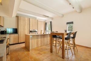 een keuken met houten kasten en een tafel en stoelen bij Propriété d'exception - Piscine et Tennis in Venelles