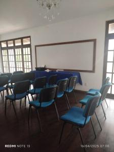 ein Klassenzimmer mit blauen Stühlen und einem weißen Brett in der Unterkunft Casa grande para o São João in Campina Grande