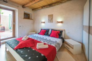 a bedroom with a bed with red pillows and a window at Villa Irena, a romantic villa nestled in the heart of Istria in Pulići +22 photos