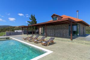 a pool with lounge chairs and a house at ElaionHill-villa in Gennadi