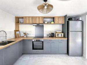 a kitchen with a stainless steel refrigerator and wooden cabinets at L'Heure dorée, au coeur du Beaujolais in Lacenas