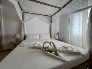 a white bed with towels and flowers on it at Casa Sanaa - Sea view in Watamu +42 photos