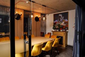 a dining room with a wooden table and yellow chairs at Loop Hotel Vilnius in Vilnius