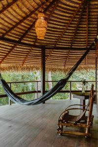 a hammock in a straw hut with a table and a chair at Villa Arapiuns - 6 Bangalôs na Floresta in Santarém