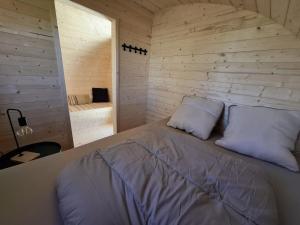 a bed in a room with a wooden wall at Le Cabanon du camping 2 in Bannes