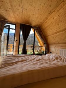 ein Schlafzimmer mit einem großen Bett und einem großen Fenster in der Unterkunft Chalet Green in Cazaci