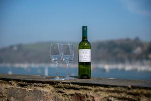 a bottle of wine sitting next to two wine glasses at Riverside Apartment with Stunning Views & Patio in Dartmouth +33 photos