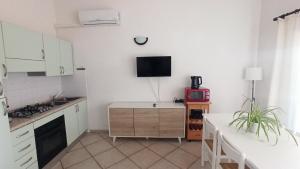 Il comprend une cuisine avec des placards blancs et une télévision murale. dans l'établissement Casa Isabel, à Budoni