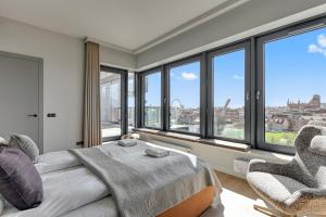 a bedroom with a bed and a chair and windows at Blue Mandarin Riverside Premium Sauna & Gym in Gdańsk