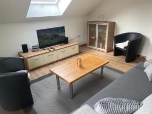 a living room with a couch and a tv and a table at Eifelbrise in Simmerath