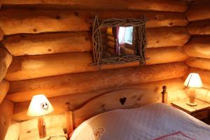 een slaapkamer in een blokhut met een bed en een spiegel bij Gite En Rondins in Janvry