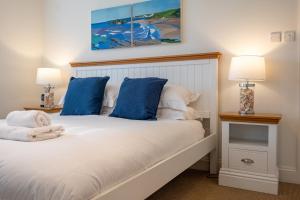 a bedroom with a white bed with blue pillows at Family-friendly Bungalow Near Thurlestone Beach in Thurlestone