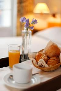 bandeja con una cesta de pan y un vaso de zumo de naranja en Hotel La Manufacture, en París
