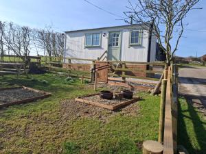 a garden with a fence and a house at Lowgingerfield Shepherd Hut in Richmond +10 photos