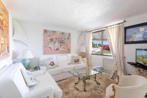 a living room with white furniture and a window at Cala di Volpe - Villa con vista mare e golf club in Abbiadori